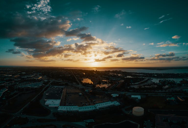 Aerial view of contemporary town district with low level buildings near peaceful river at sunset