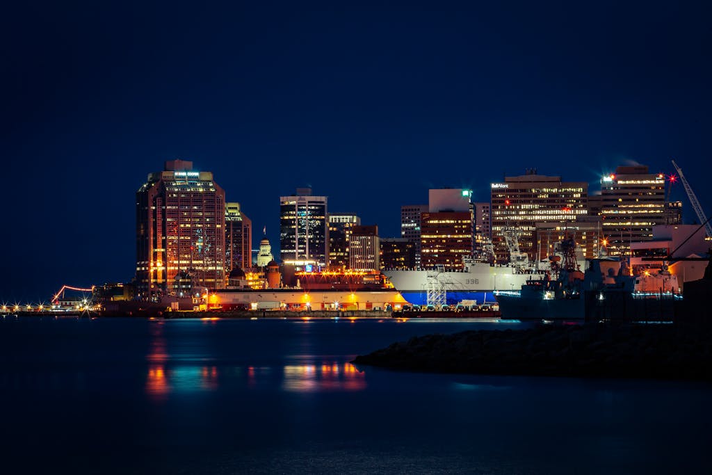 Illuminated Halifax skyline along the waterfront, featuring striking city lights reflected in the harbor at night.