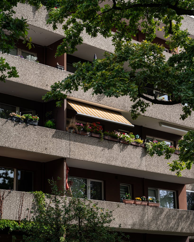 Modern residential building with balconies adorned with flowers and summer greenery.